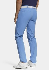 Lichtblauwe golfbroek met een gladde textuur, taps toelopende pasvorm en een witte geweven riem. Beschikt over een achterzak met ritsdetail. Witte golfschoenen.