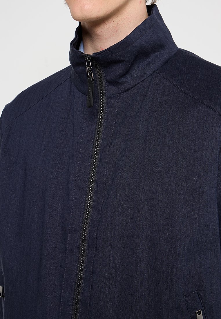 Marineblaue Jacke mit hohem Kragen und Frontreißverschluss, strukturiertem Stoff und Seitentaschen. Schlichtes Design mit minimalen Hardware-Akzenten.