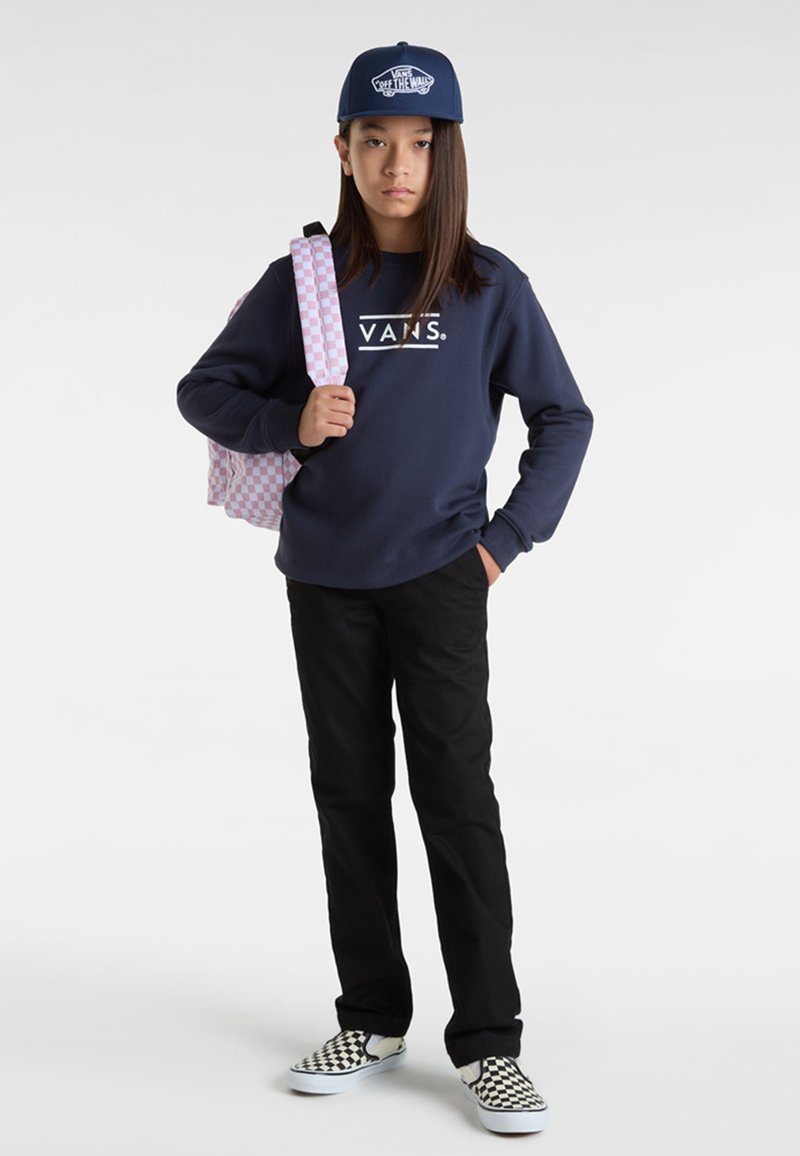 Felpa navy con logo "VANS", pantaloni neri, scarpe slip-on a scacchi e uno zaino a quadretti rosa e bianco. Un cappellino di jeans completa il look.