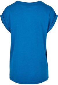 T-shirt in cotone blu con maniche arrotolate, scollatura tonda e vestibilità rilassata. Tessuto morbido e spacchi laterali vicino all'orlo per facilitare i movimenti.