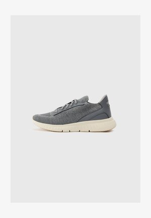 Baskets de sport grises avec des tiges en tissu texturé, une semelle en caoutchouc gris clair et des lacets noirs. Présentent un logo sur le côté.