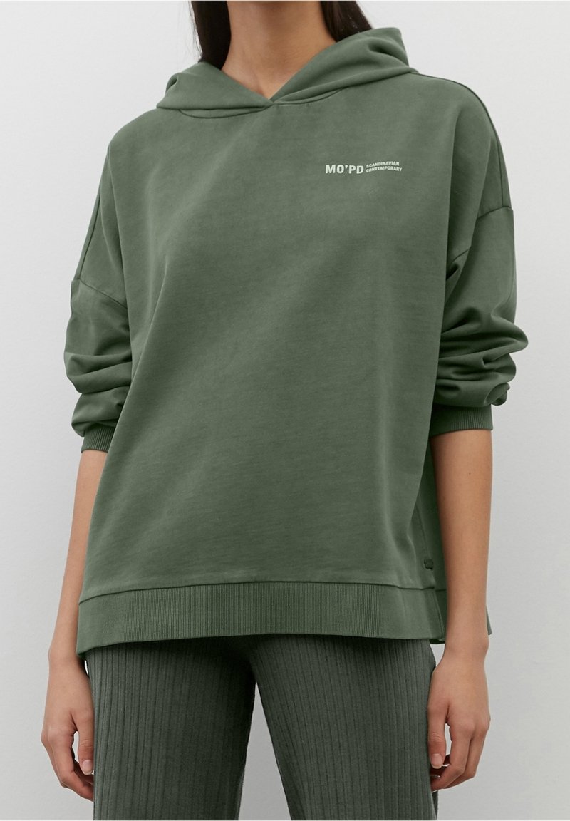 Sudadera verde con capucha de corte relajado, con puños y dobladillo acanalados. Presenta un pequeño logo blanco en la parte superior izquierda.