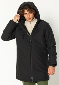 Zwarte parka met verstelbare capuchon, ritssluiting en twee voorzakken. Het materiaal lijkt waterafstotend met een gladde textuur.