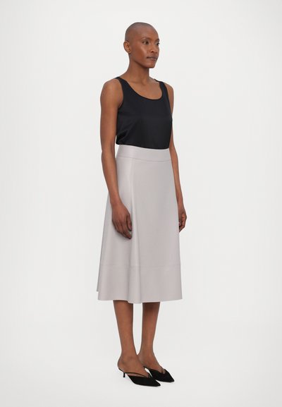 Svart satintopp, lys grå flagrende midiskjørt, glatt tekstur, ingen synlige mønstre. Brukt med svarte spisse hæler.