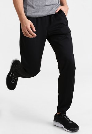 Pantalons de sport noirs en matériau léger, dotés d'une taille élastique, de poches latérales et d'une coupe fuselée.