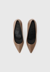 Escarpins à bout pointu en cuir marron avec des semelles intérieures noires. Texture lisse avec un design minimaliste et un logo de marque embossé à l'intérieur.
