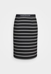 Svart-och-vit randig kjol med en figurnära design, med en elastisk midja märkt "CALVIN KLEIN JEANS." Slen yta, knälängd.
