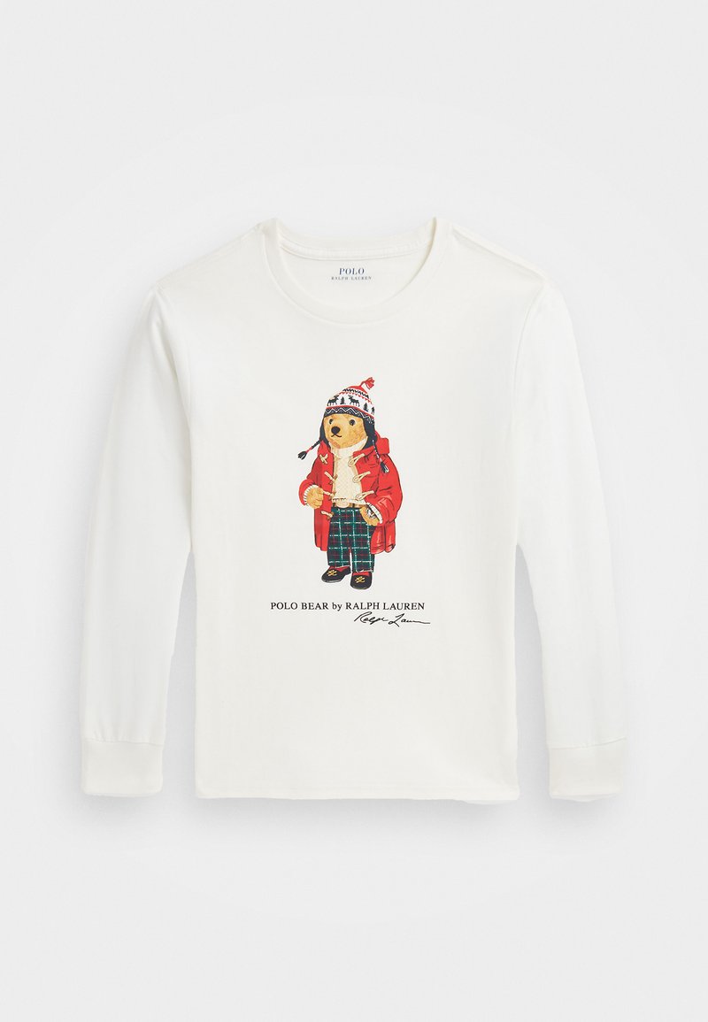 Kreminė ilgomis rankovėmis marškinėliai su meškos personažu raudoname paltuke, megztu švarkeliu ir languotais kelnais. Po figura užrašyta "Polo Bear by Ralph Lauren".