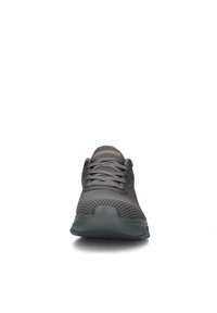 Scarpa sportiva grigia con tomaia in rete, punta rotonda e suola in gomma flessibile. Presenta un design testurizzato e chiusura con lacci.