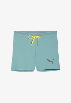 Tirkīzzilas peldēšanas šorti ar dzeltens auklu jostasvietā un melnu Puma logotipu kreisajā kājiņā, izvietoti plakani uz baltas virsmas.