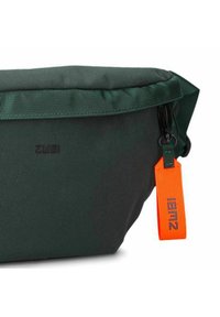 Bolso de hombro de color verde oscuro hecho de un tejido duradero. Cuenta con un cierre con cremallera, una correa texturizada y una etiqueta naranja brillante con la marca.