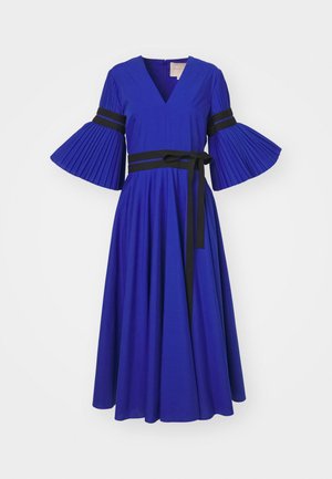 Kraljevsko plava haljina s V-izrezom, nabranim zvonastim rukavima i crnim pojasom. Prošireni suknja s glatkom teksturom tkanine.