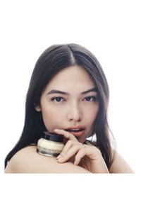 Vitaminangereicher Gesichtsgrund in einem runden Glasbehälter mit einem schwarzen Deckel. Cremige Textur, hellgelbe Farbe, mit einem Etikett, das schwarzen Text zeigt.