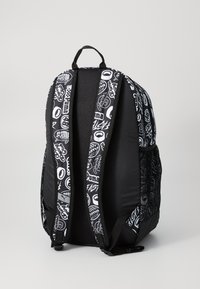 Black backpack featuring a mix of graphic prints in white. The design includes padded straps and a textured side panel.