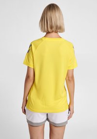 Gul sporttröja med korta ärmar, som har en texturerad mesh-tyg och grå detaljer på axlarna. Bakvy visas.