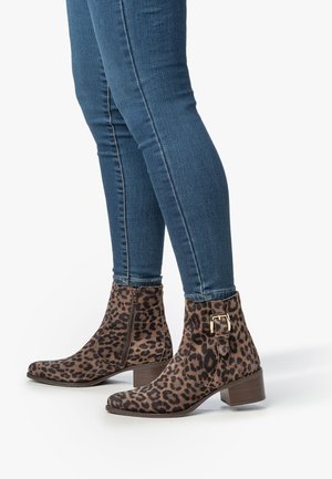 Leopard print ankle boots made of soft suede, featuring a rounded toe, side zip, and a chunky heel; paired with fitted blue jeans.