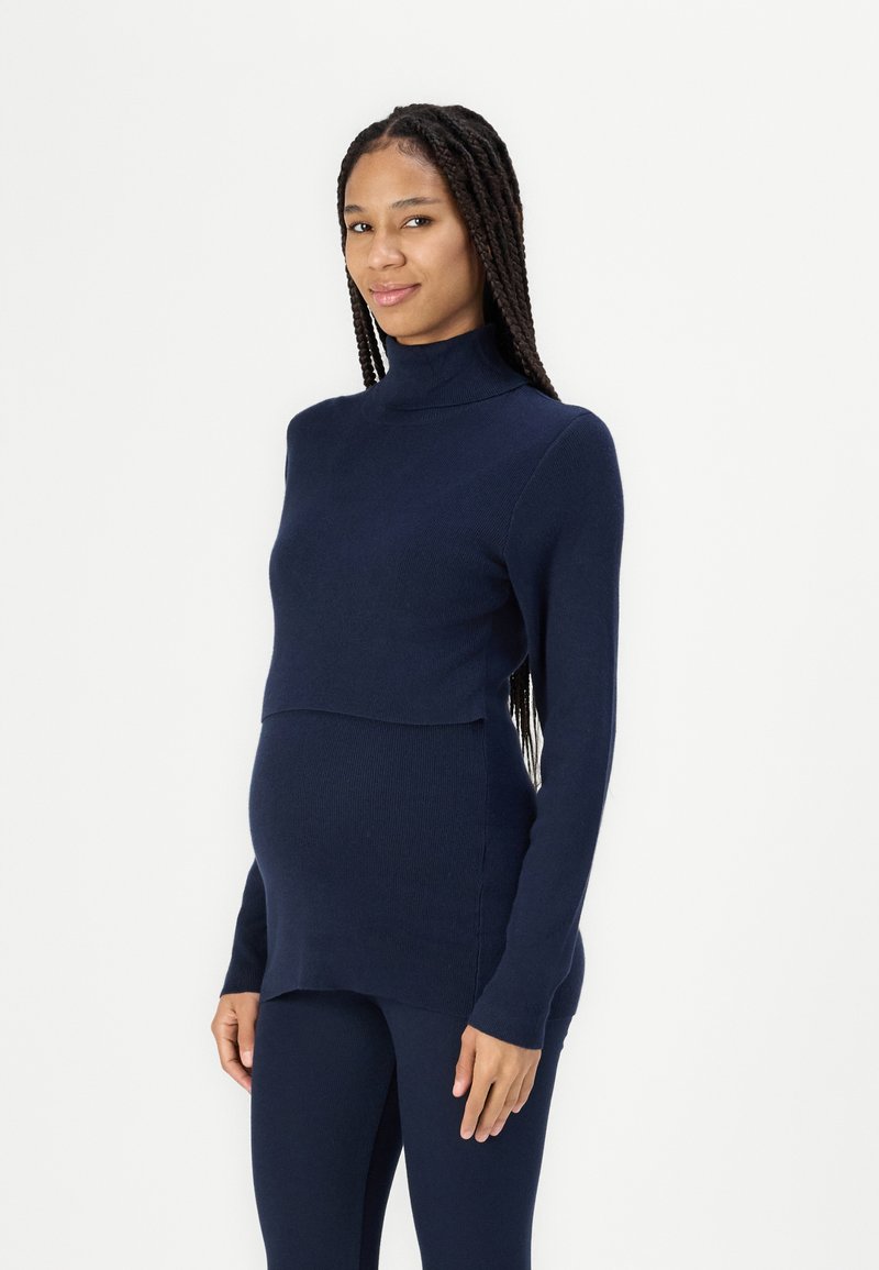 Maglione a collo alto in maglia a coste di colore blu navy per maternità, con un design frontale a strati e maniche lunghe, abbinato a leggings coordinati.