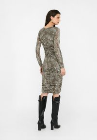 Rochie midi cu imprimeu leopard, cu mâneci lungi, detalii pliate și o siluetă ajustată. Purtați cu cizme negre cu toc până la genunchi.