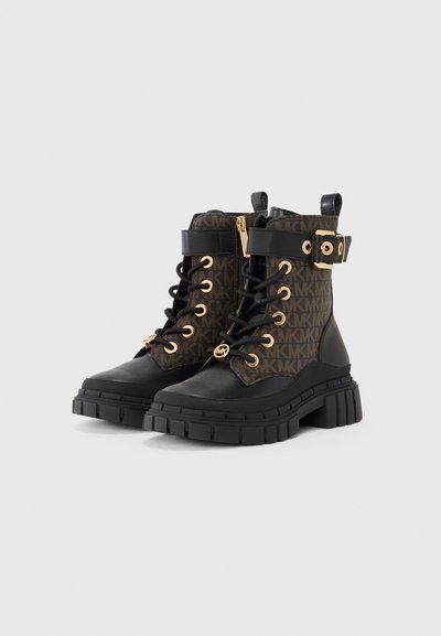 Bottines noires et brunes avec quincaillerie dorée, dotées d'un dessus en tissu à motif, d'une semelle épaisse, d'un laçage à l'avant et d'une fermeture éclair sur le côté.