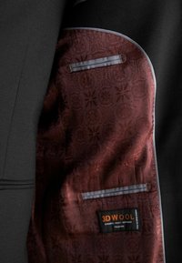 Sacou negru cu o căptușeală cu model vișiniu, având un buzunar lateral și un etichetă cu inscripția "3DWOOL." Material texturat și detalii în contrast.