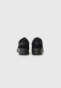 Black athletic shoes feature a mesh and suede upper, rugged sole, and pull tab at the heel. The design is minimalistic with no notable accents.