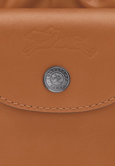 Brown leather purse with a textured finish, featuring a silver-tone hardware button and embossed logo accent.