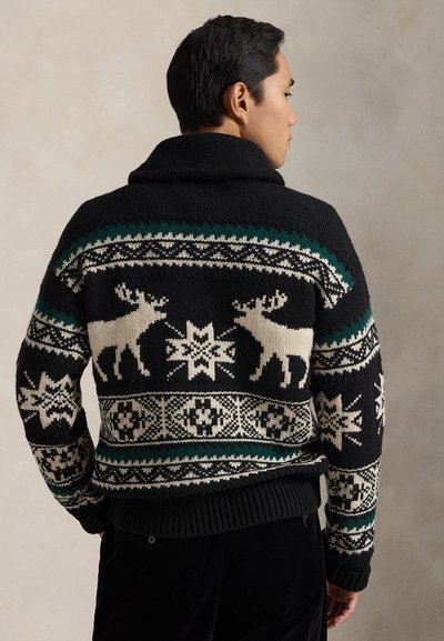 Μαύρο πλεκτό πουλόβερ με μοτίβο fair isle που περιλαμβάνει λευκά ελάφια, νιφάδες χιονιού και πράσινες πινελιές. Με παχύ γιακά και ριμπ μανσέτες.