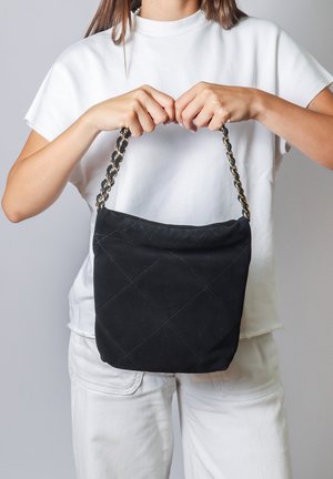 Borsa a spalla nera trapuntata con tracolla a catena. Texture liscia, forma rettangolare e parte superiore arricciata. Misura approssimativamente di dimensioni medie.