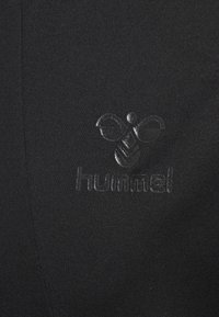 Zwarte sportkleding met een gladde textuur. Bevat een tonale reliëflogo van het merk "hummel" nabij het midden.
