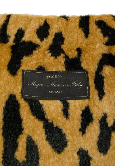 Pelliccia sintetica color beige con macchie nere a forma di leopardo, caratterizzata da un'etichetta nera con la scritta "Dal 2009 Msgm Made in Italy Milano" con cuciture dorate.