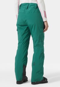 Grüne wasserdichte Skihose mit lockerer Passform, Cargo-Tasche und verstärkten schwarzen Bündchen. Hergestellt aus strapazierfähigem synthetischem Material.