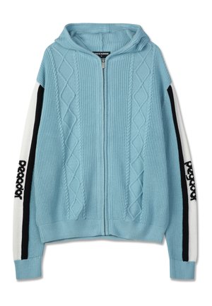 Ανοιχτό μπλε φούτερ με φερμουάρ και σχέδιο διαμαντιού. Διαθέτει λευκά μανίκια με μαύρες λεπτομέρειες και λογότυπο. Υφασμάτινη πλέξη με υφή.
