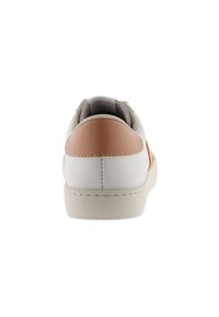 Zapatilla blanca con parte superior de cuero liso, con un acento de cuero marrón claro en el talón y una suela de goma beige, diseño minimalista.