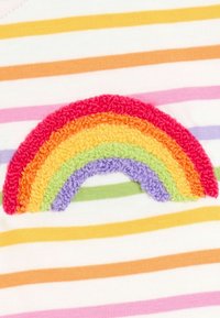 Rövid ujjú felső fehér pamut anyagból, multicolor vízszintes csíkokkal és élénk színekben pompázó textúrált szivárvány applikációval.