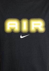 Svart bomull T-skjorte med fet "AIR" tekst i gul og hvit med konsentriske linjer, samt en liten hvit Nike swoosh-logo.