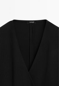 Abbigliamento nero con design a V. Tessuto liscio con un aspetto pulito e minimalista. L'etichetta riporta "Massimo Dutti", indicando l'origine del marchio.