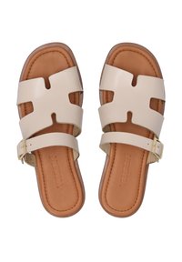 Beige sandaler med brede udskæringer og en brun fodseng. Udstyret med en gyldent justerbart spænde på en rem. Flad sål, struktureret læder.
