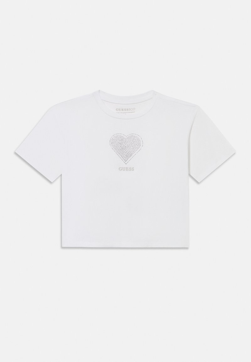 Valge lühendatud T-särk lühikeste varrukatega, ümmarguse kaelusega, rhinestone südamekujundusega ja südame all keskel paigutatud "GUESS" logoga.