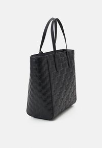 Sac fourre-tout noir en matériau texturé, arborant un motif de logo en relief, un fond plat et deux poignées supérieures. Le design est rectangulaire avec des bords lisses.