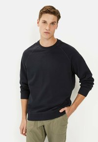 Navyblauwe sweatshirt met een ronde halslijn, lange raglanmouwen en geribbelde manchetten. De stof heeft een gladde textuur en een losse pasvorm.