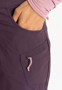 Bolsillo de tela púrpura con un detalle de cuerda rosa. El diseño presenta una textura suave y una costura lateral para funcionalidad.