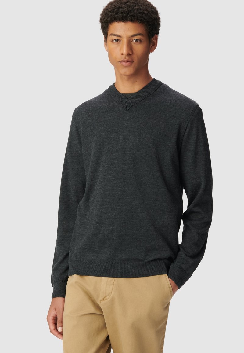 Ciemnoszary sweter z dekoltem w serek, długimi rękawami, prą�żkowanymi mankietami i dołem, w połączeniu z beżowymi spodniami chinos. Miękka tekstura, luźny krój.