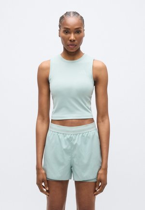Svetlozelený atletický crop top s okrúhlym výstrihom, v kombinácii so zodpovedajúcimi šortkami. Obe položky sú vyrobené z hladkej, ľahkej tkaniny.