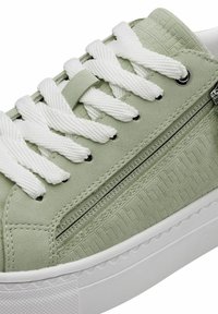 Sneaker verde con texture e lacci bianchi, dotato di una cerniera laterale e di accenti a motivi sottili sulla parte superiore. Suola in gomma bianca.