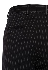 Zwarte stoffen broek met witte streepjes, uitgerust met een slanke tailleband, een knoopzak en een getailleerde pasvorm. Gemaakt van een gekamd wolmix.