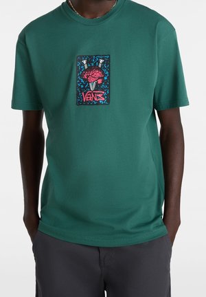 Camiseta de manga corta en color verde azulado, hecha de algodón, con un estampado gráfico en rosa y azul sobre un fondo negro y detalle de logo.