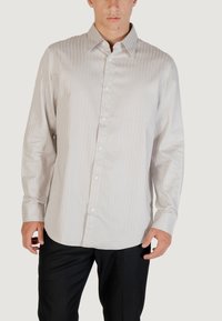 Camicia a maniche lunghe grigia chiara con righe verticali, chiusura con bottoni sul davanti e colletto classico. Tessuto morbido e vestibilità leggermente sagomata.