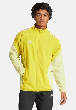 Gelbe Sportjacke mit durchgehendem Reißverschluss, langen Ärmeln und weißen Akzenten. Mit adidas-Logo und drei weißen Streifen auf den Schultern.