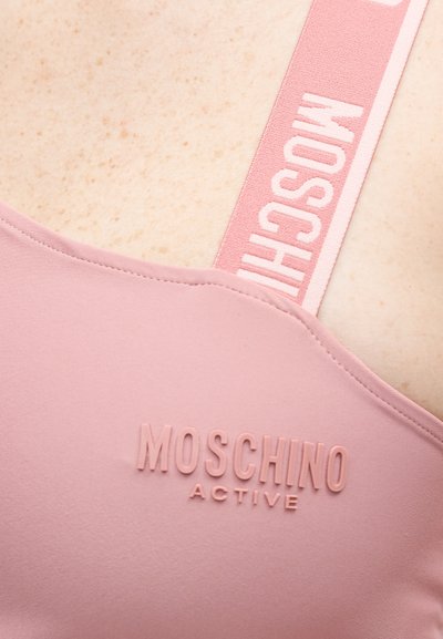 Ροζ αθλητικό σουτιέν με το λογότυπο "MOSCHINO ACTIVE" ανάγλυφο μπροστά και ταιριαστή λουρίδα με εμπορικό σήμα σε ανοιχτό χρώμα δέρματος.