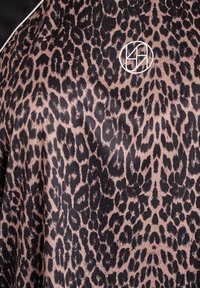 Tela de estampado de leopardo en tonos negros y marrones con una textura suave y brillante. Un logo blanco está posicionado en el centro a la derecha.
